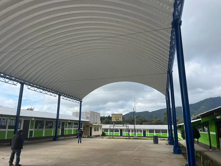 Vista bajo el techo curvo de una cancha escolar