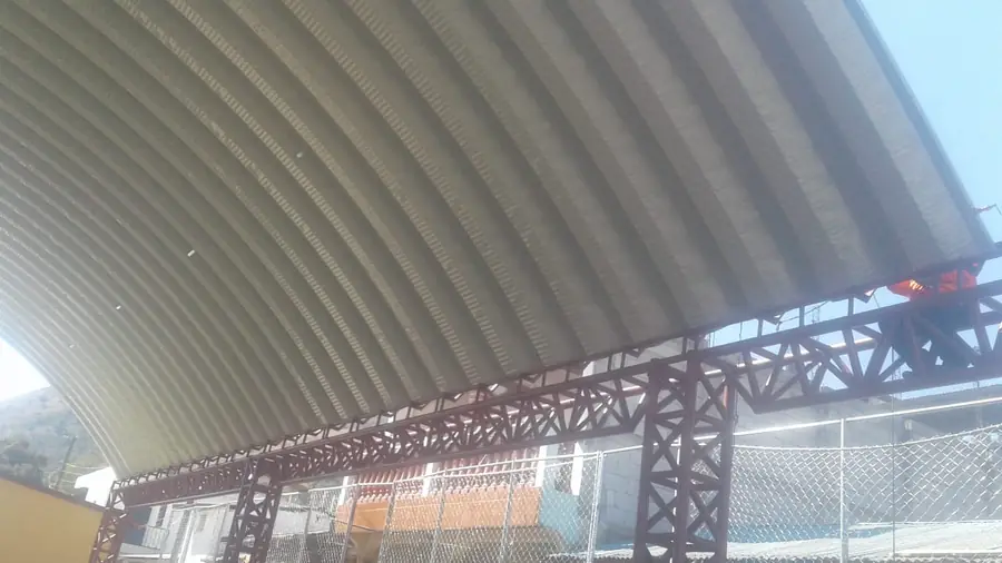 Cancha techada con cerchas rojas, vista desde abajo